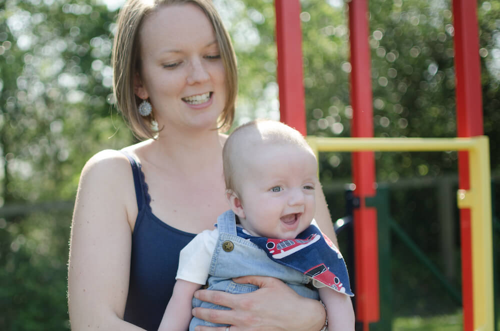 Ethan smiling on Laura's lap while on a swing.